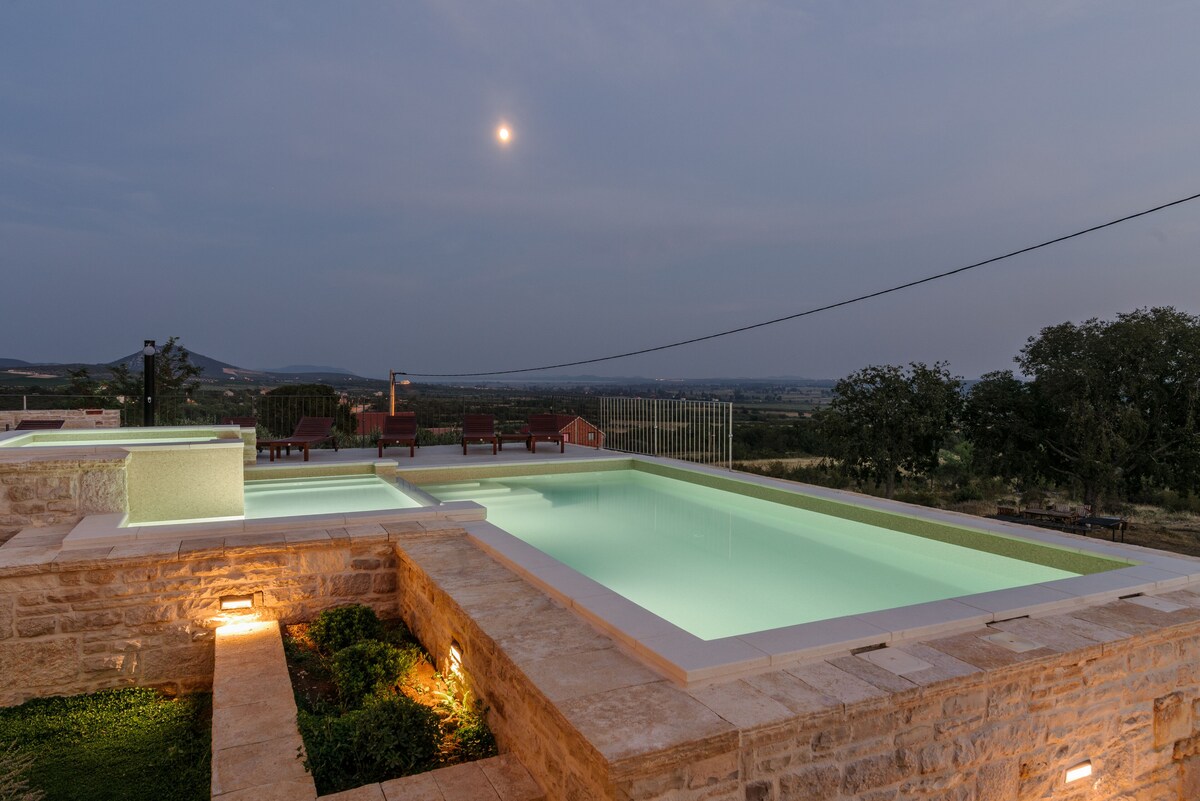 Night view of the illuminated heated pool at Authentic Stone Villa
