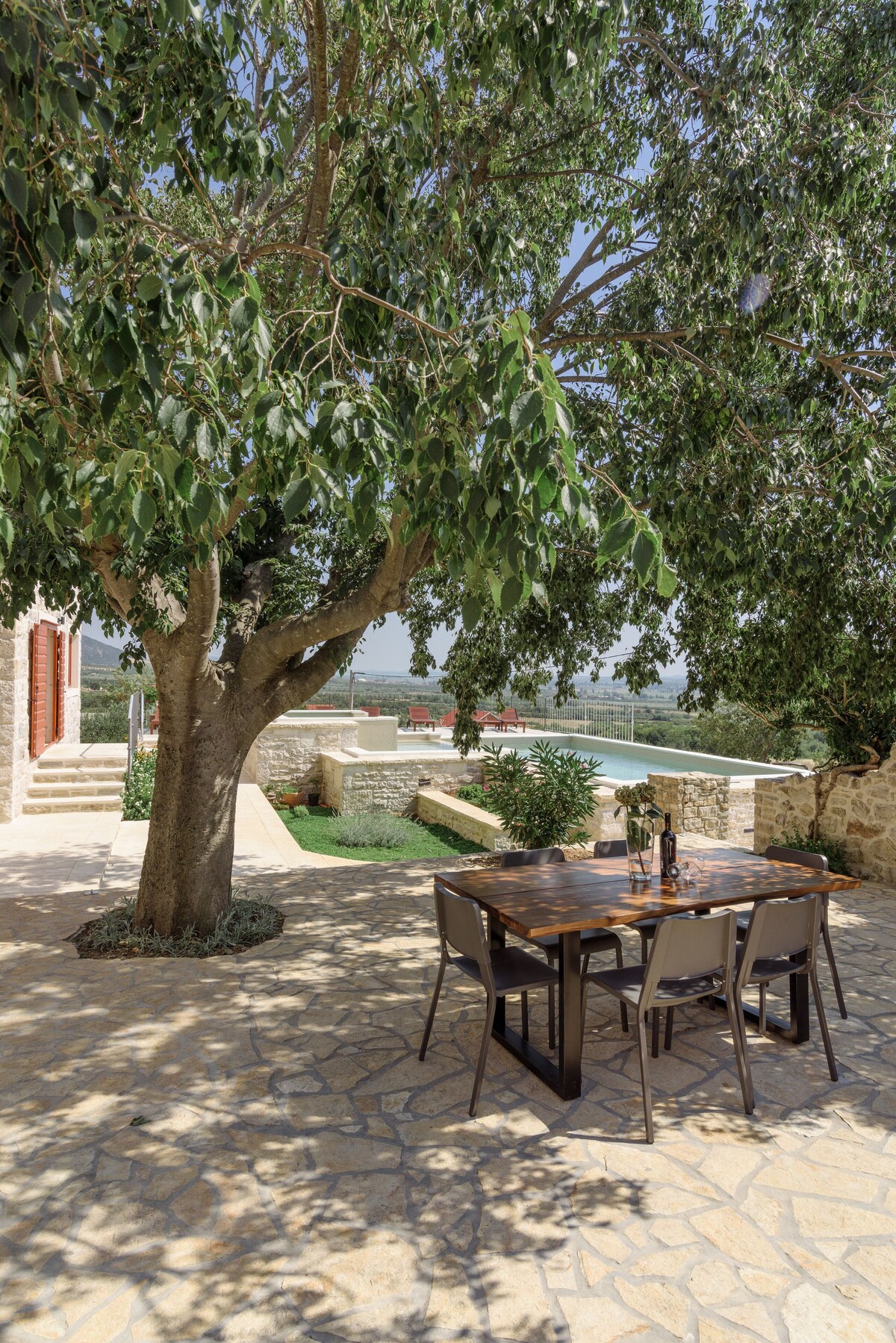 Shaded outdoor dining area beneath a large tree at Authentic Stone Villa